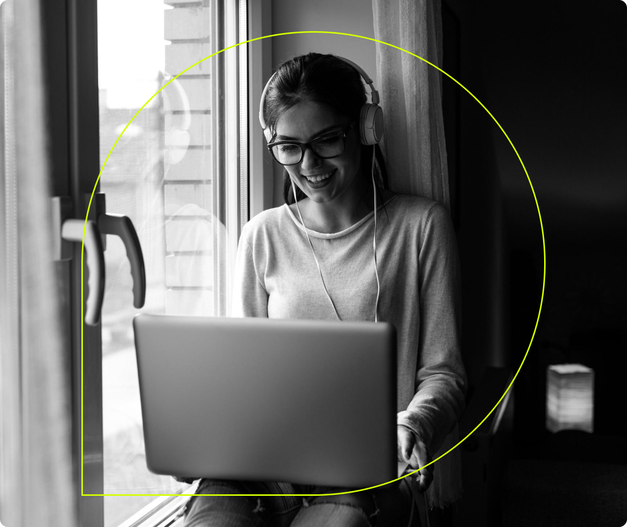 A person works on a laptop beside a large window.